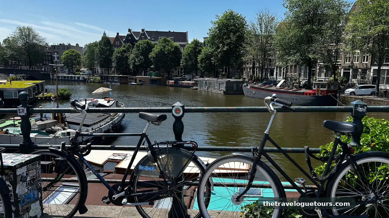 Bicycles parked on a bridge over a canal in Amsterdam with traditional Dutch buildings