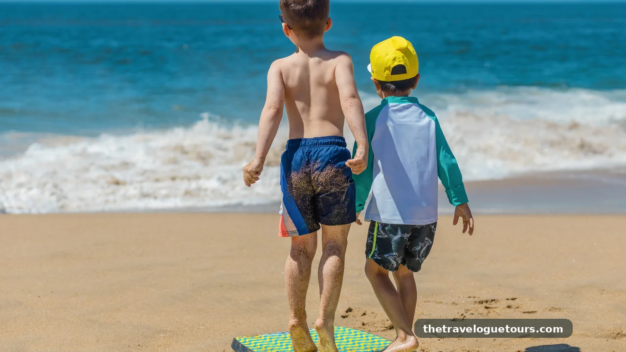Two children playing on the beach with a bodyboard on a sunny day