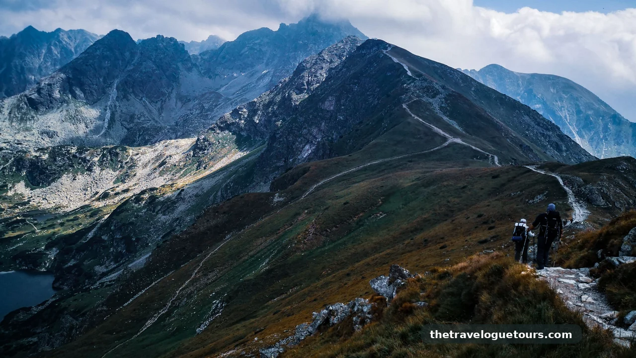 Hikers walking a scenic mountain path under a dramatic sky