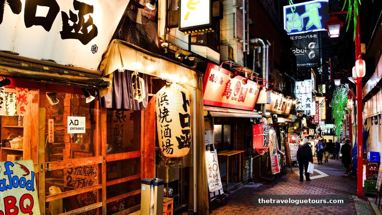 A lantern-lit alley in Shinjuku, Tokyo at night with people walking past small glowing eateries