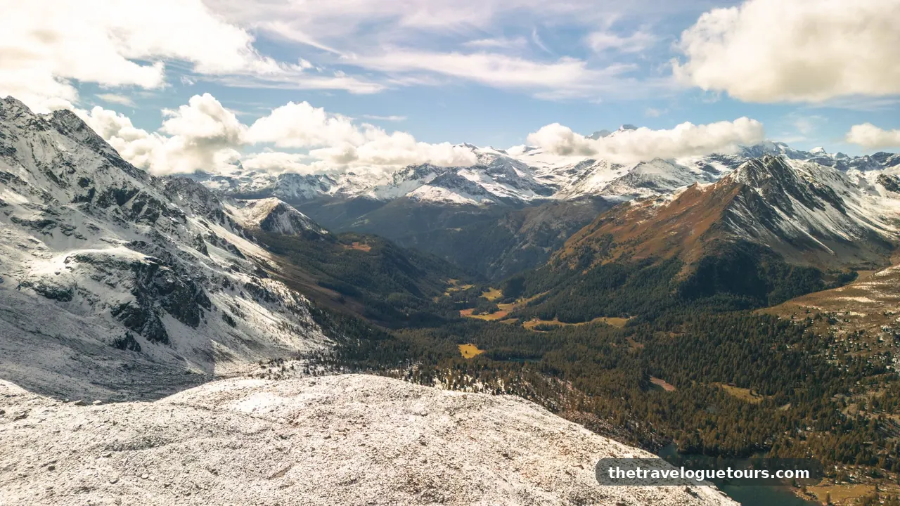 An aerial view of the snow-covered Swiss Alps under a bright blue sky